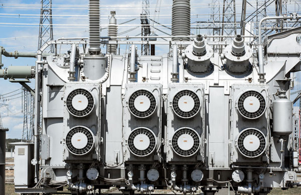 Electric power transmission lines. High voltage switchgear and equipment in front of power plant.
