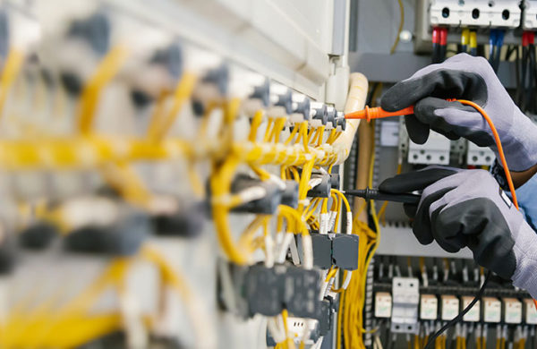Electrical engineers test electrical installations and wiring on protective relays, measuring them with a multimeter.